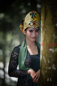 Portrait of young woman standing against trees