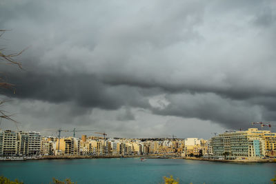 Buildings in city against cloudy sky