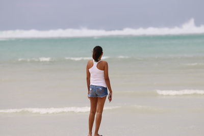 Rear view of woman standing at beach