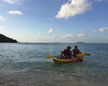 People relaxing on beach against sky