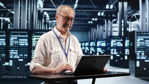 Portrait of man using laptop while standing in cafe