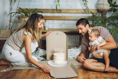 Cheerful father and mother with daughter celebrating birthday at home