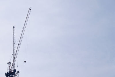 Low angle view of cranes at construction site against sky