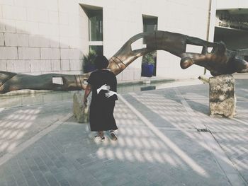 Rear view of woman walking on sidewalk in city