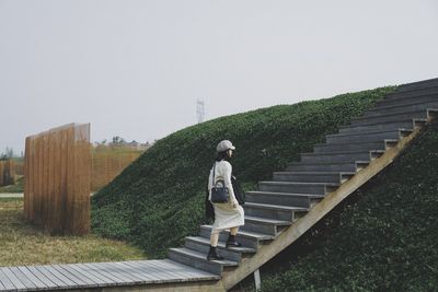 Rear view of man standing on staircase against sky