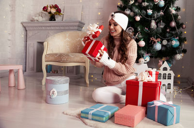 Happy woman with presents in front of the christmas tree. stylish female in cozy knitted sweater
