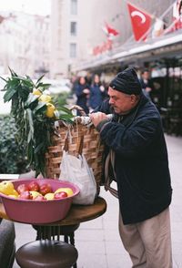 Man stabding by fruits and basket on table in city