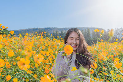 Woman standing by yellow flowering plants