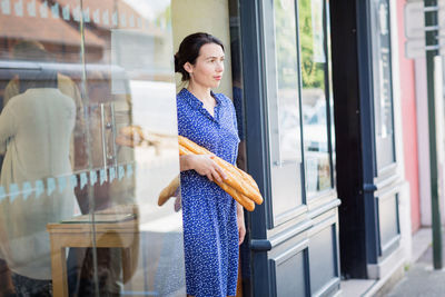 Young woman buying a french baguette