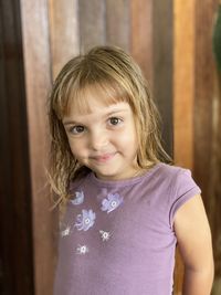 Portrait of cute smiling girl standing against wall