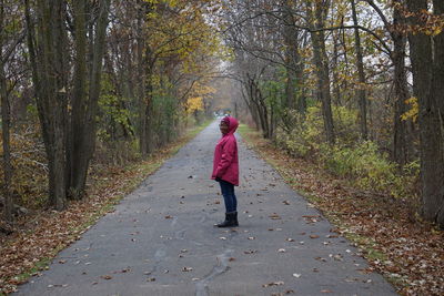 Woman walking on footpath amidst trees in forest