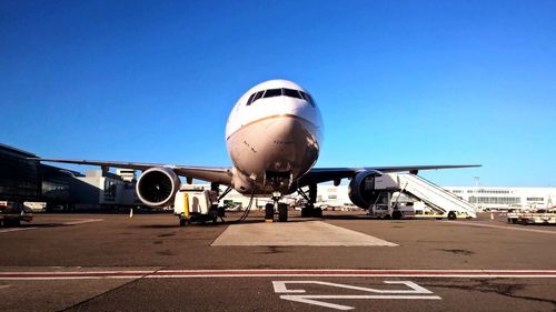 Low angle view of airplane on runway against clear blue sky