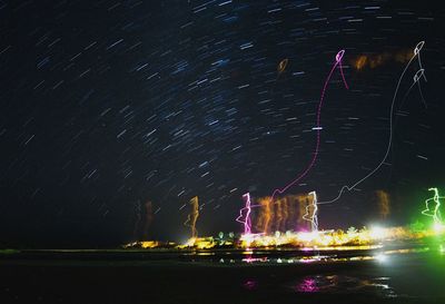 Firework display over sea against sky at night