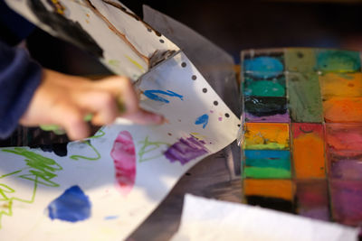 Cropped hand of child painting on paper at table