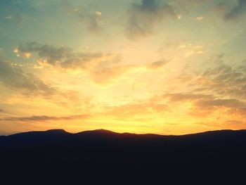 Scenic view of silhouette mountains against orange sky