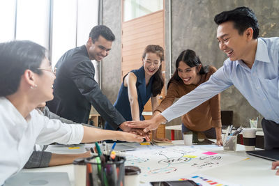 Smiling colleagues stacking hands at office