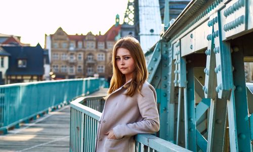 Portrait of beautiful young woman standing against railing