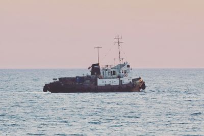 Boat sailing in sea against clear sky during sunset