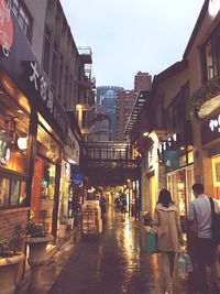 People walking on illuminated street at dusk