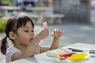 Close-up of cute girl playing with childs play clay at table outdoors