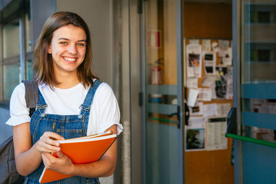 Portrait of smiling teenage girl holding books