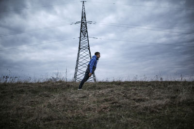 Side view full length of man bending forward on field against sky