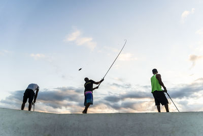 Rear view of people on beach against sky