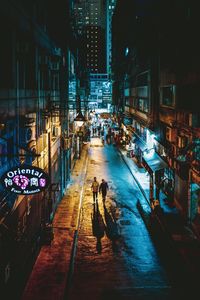 People walking on illuminated city street at night