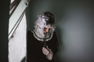 Portrait of woman standing against wall at home