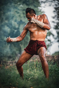 Full length of shirtless man lying on field