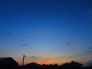 Low angle view of silhouette electricity pylon against sky