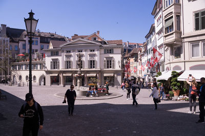 Group of people walking on road along buildings