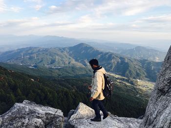 High angle view of young man walking on mountain against sky