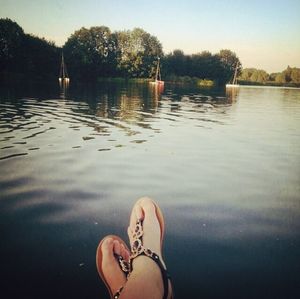 Low section of person standing in lake