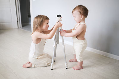 Cute kids siblings understand looking at tripod at home in bright interior