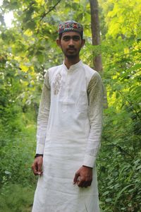 Portrait of young man standing against trees