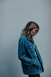 Thoughtful woman wearing denim jacket while standing outdoors