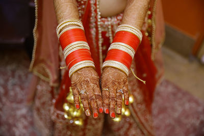 Midsection of bride wearing bangles and henna tattoo during wedding ceremony