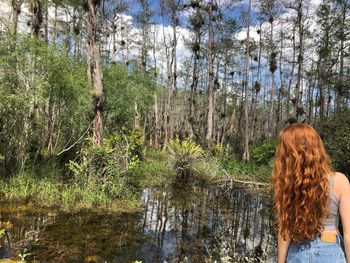 Rear view of woman standing in forest