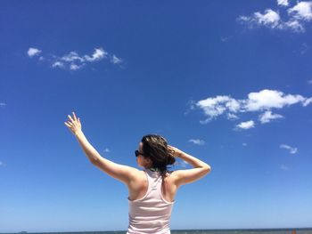 Rear view of woman standing against blue sky