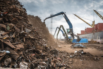 Cranes at junkyard against sky