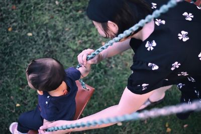 High angle view of mother swinging child at playground