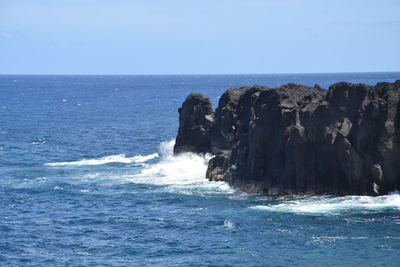 Rock formation in sea against clear sky