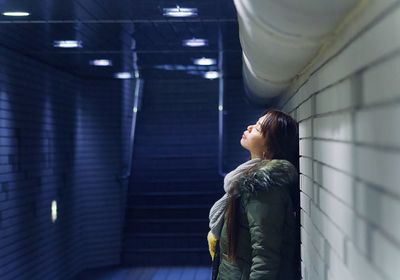 Side view of woman standing against wall