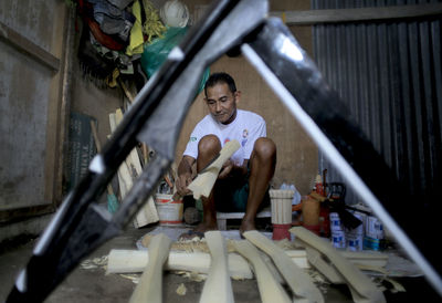 A craftsman finishes making a traditional salawaku shield weapon from cork wood in ternate city