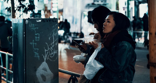 Side view of woman drinking glass on table