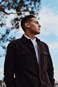 Low angle view of young man standing against sky