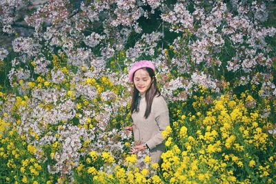 Portrait of woman standing by flowering plants