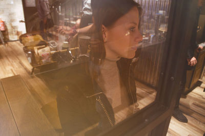 Reflection of woman on glass at restaurant