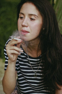 Young woman smoking cigarette at park